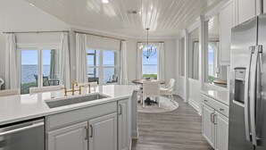 Une cuisine moderne avec des meubles blancs, des appareils en acier inoxydable et une vue sur la mer.