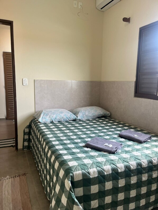 Un dormitorio con una cama, almohadas y una toalla doblada sobre la cama.