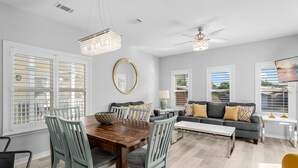 A spacious living area with a dining table, chairs, a sofa, and a TV.