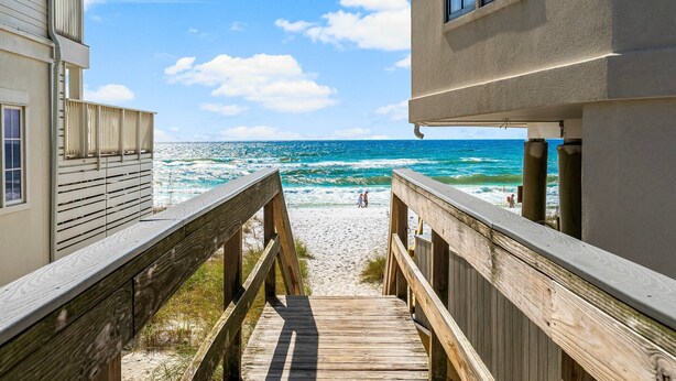 A wooden boardwalk leading to a beach with a clear view of the ocean.