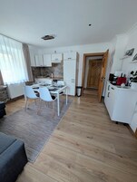 Una cocina moderna con armarios blancos, un comedor con mesa dispuesta para cuatro personas y piso de madera.