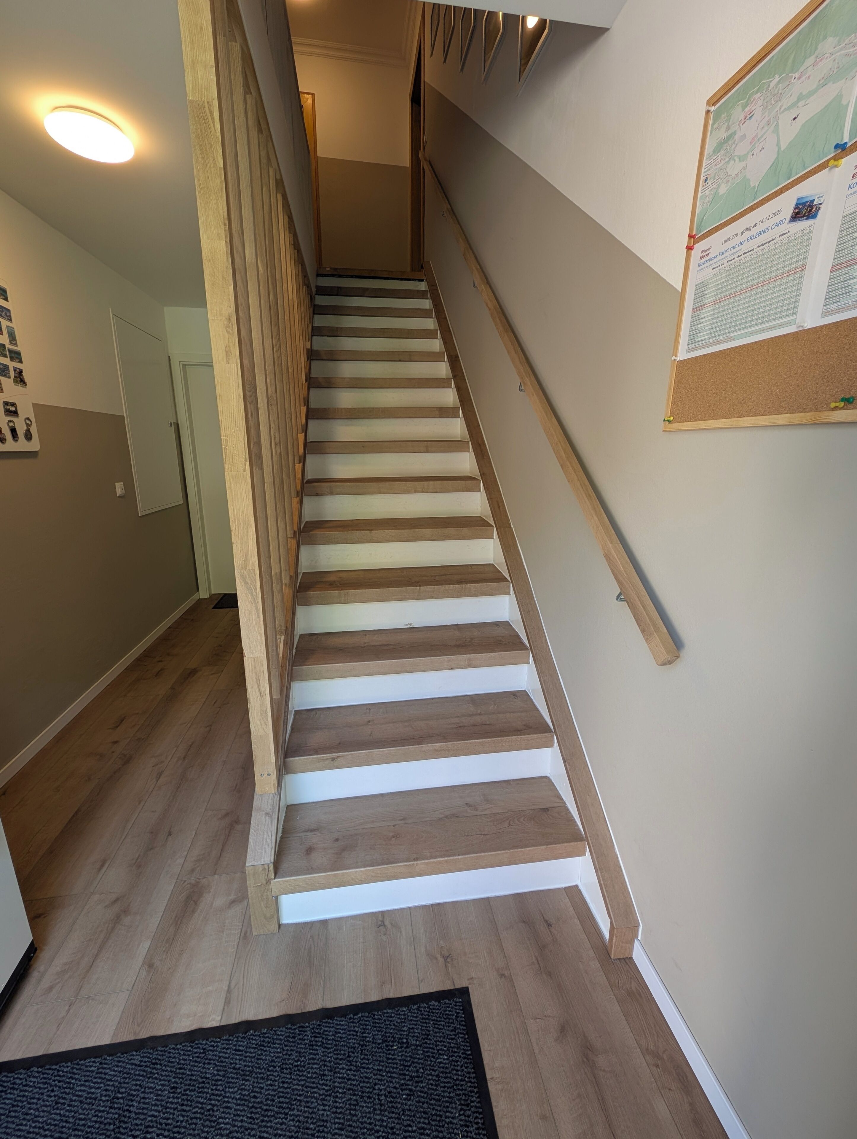 Una escalera de madera con barandilla que conduce a una plataforma con un tablón de anuncios.