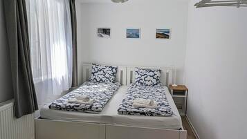 Ein Schlafzimmer mit Bett, Nachttisch, Lampe und farbenfrohem Teppich.