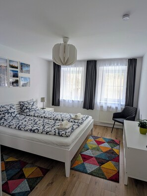 A modern bedroom with a large bed, a desk, and a chair.