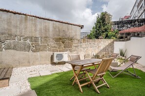 A patio with a table and chairs, a stone wall, and an air conditioning unit. - GuestReady - The perfect urban retreat (Porto)