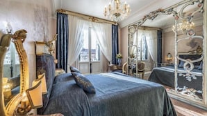 Un dormitorio clásico con una cama grande, un espejo decorativo y una araña.