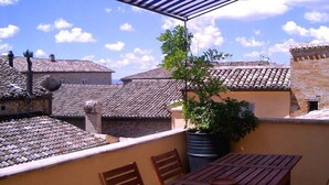 A terrace with a table and chairs, a potted plant, and a view of neighboring buildings with tiled roofs. - Penthouse to LIVE: in PALACE with terrace (Fermo)