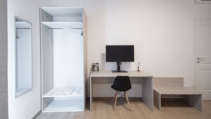 A room with a built-in wardrobe, a desk with a computer, and a chair.