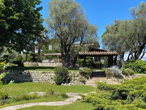 Escape to a serene garden oasis with a traditional stone house and lush greenery.