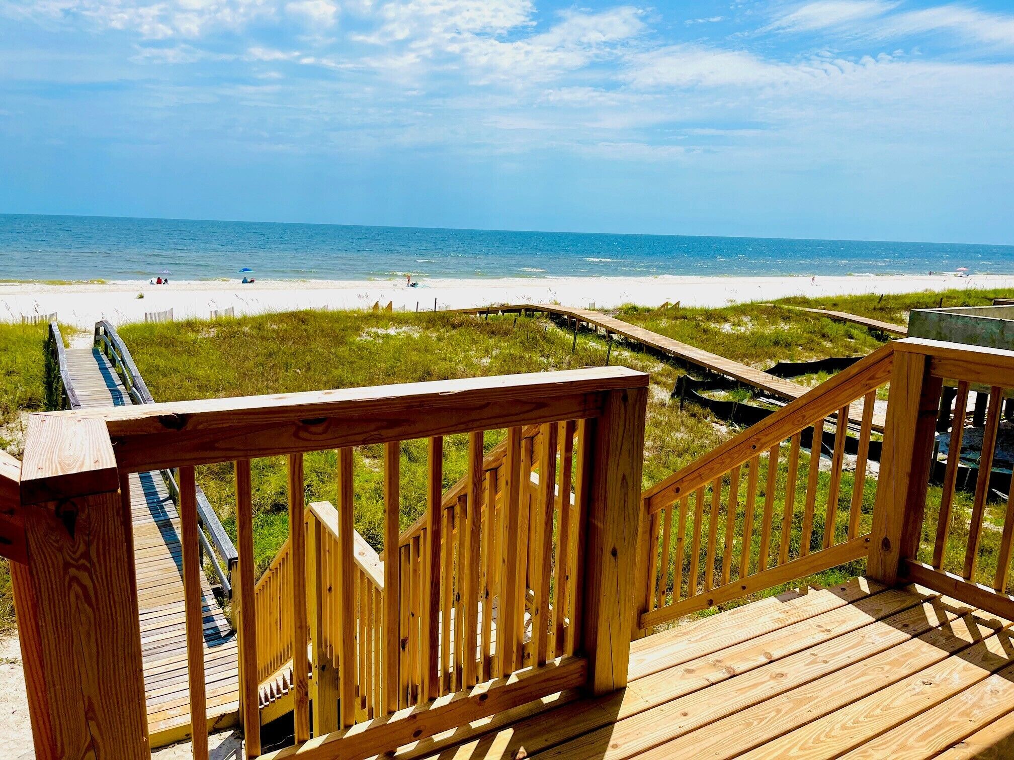 A wooden deck with a view of a beach and ocean.