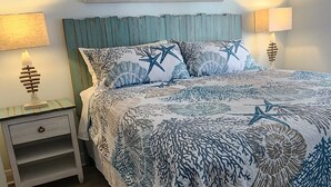 Una camera da letto con un letto, due comodini, una testiera e un quadro appeso al muro.