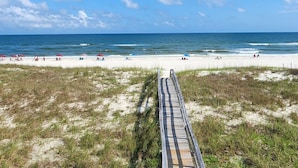 Une plage avec une promenade en bois menant à la rive, une plage de sable et l’océan.