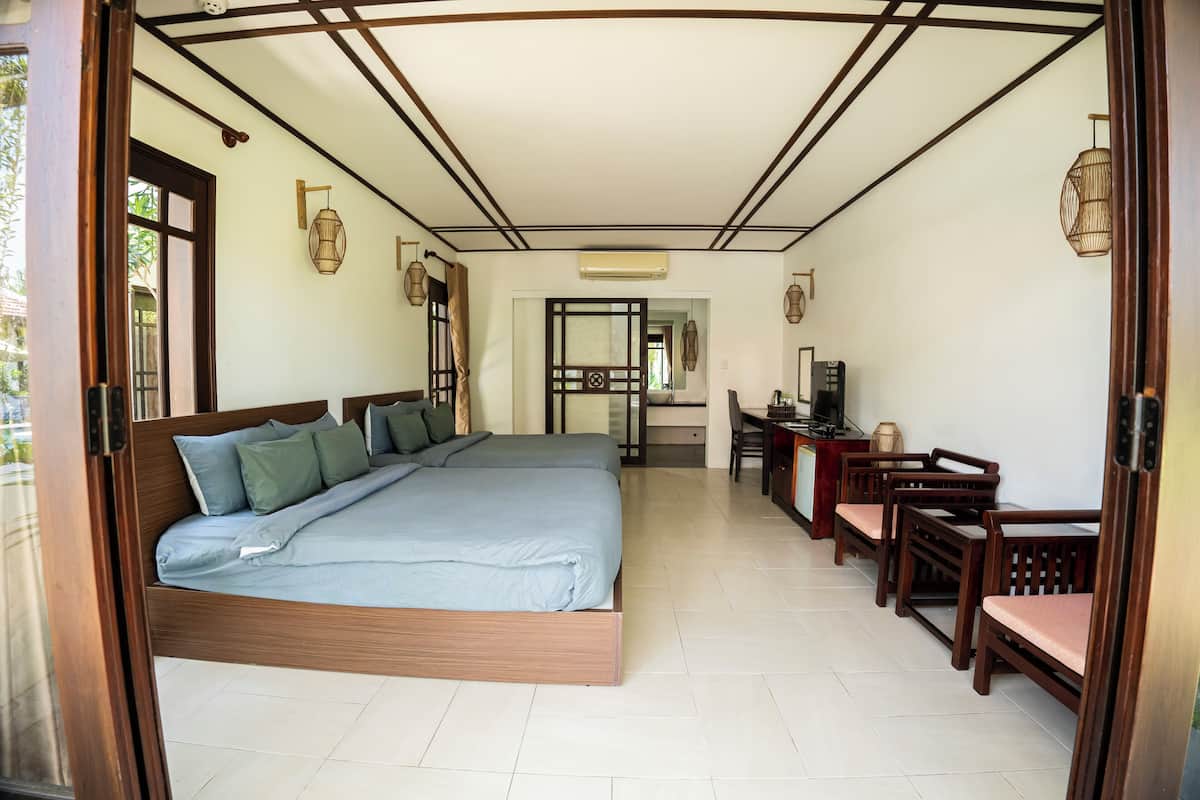 A bedroom with a large bed, wooden headboard, and a desk with chairs.