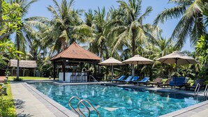 A swimming pool with lounge chairs and umbrellas, surrounded by palm trees. - Riverside Bamboo Resort - Hoi An (Da Nang)