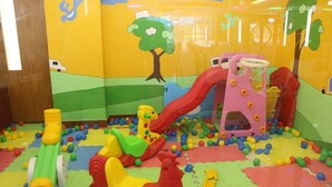 Un área de juegos infantiles con un tobogán, estructuras para escalar y pelotas de colores.