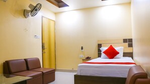 Una habitación de hotel con una cama, un sofá, una mesita y un ventilador.
