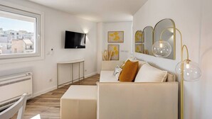 Una sala de estar moderna con un sofá, un televisor y obras de arte en la pared.