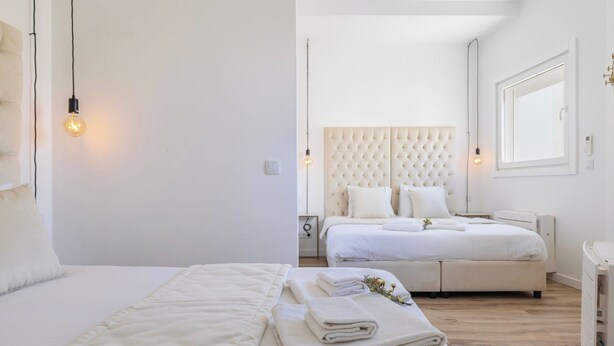 Un dormitorio moderno con una cama grande, una cama más pequeña y una mesita de noche.