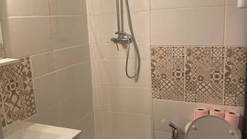 Een douche, handdoeken, zeep, toiletpapier