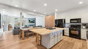 Una cucina moderna con isola centrale, mobili bianchi e forno nero.
