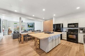 A modern kitchen with a central island, white cabinetry, and a black oven.