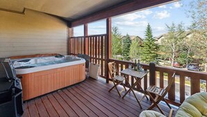 Una vasca idromassaggio su un pontile di legno con tavolo e sedie, con vista su una zona residenziale.
