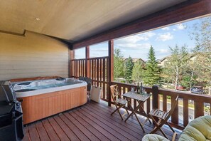 Ein Whirlpool auf einer Holzterrasse mit Tisch und Stühlen, mit Blick auf eine Wohngegend.