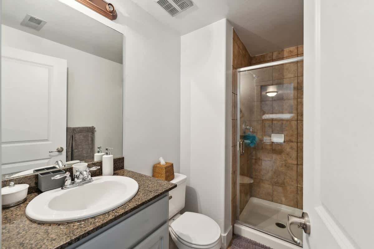 Une salle de bain équipée d’un lavabo, de toilettes et d’une douche à parois de verre.