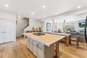 Eine geräumige Küche mit Kochinsel, Holzschränken und einem Essbereich mit Sofa und Stühlen.