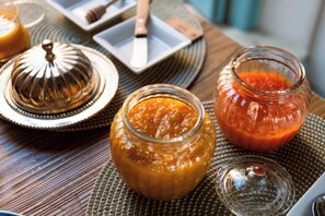 A table with jars of preserves, a honey dipper, and a knife on a woven placemat. - Planeta Country House & Beach Club (Menfi)