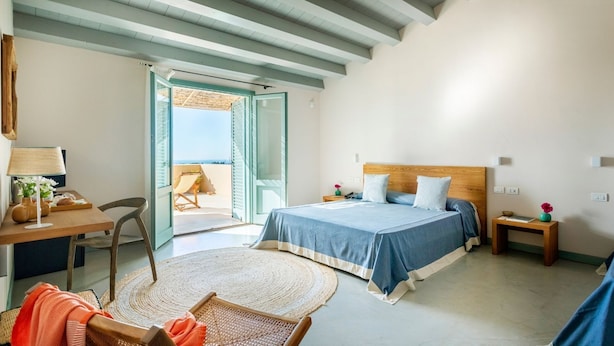 A bedroom with a bed, a desk, a chair, a small table, and a view of the outside. - Planeta Country House & Beach Club (Menfi)