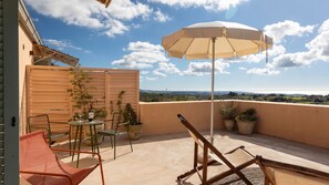 A balcony with a table, chairs, an umbrella, and potted plants. - Planeta Country House & Beach Club (Menfi)