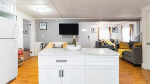 Un espacio habitable compacto con isla de cocina, comedor y zona de estar con sofá y sillones.