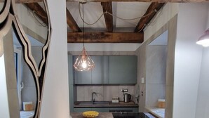 A modern kitchen with a central island, a hanging pendant light, and a rustic ceiling. - Vicolo d'Este (Tivoli)