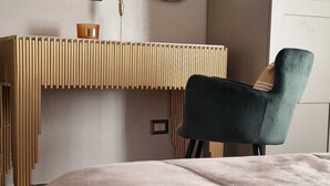 A modern bedroom with a bed, a bedside table with a lamp, and a chair. - Vicolo d'Este (Tivoli)