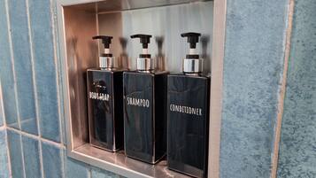 A shelf with three black bottles labeled body soap, shampoo, and conditioner.