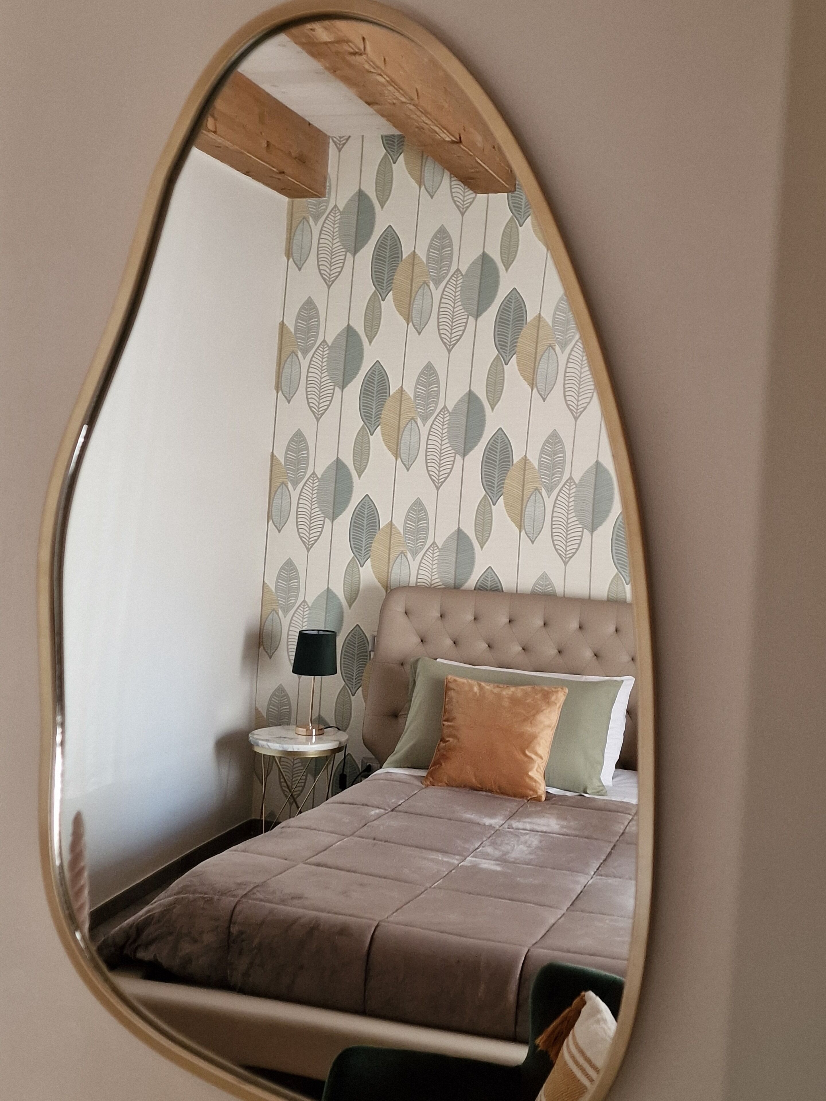 A bedroom with a tufted headboard, a bed with a brown quilt, and a nightstand with a lamp.