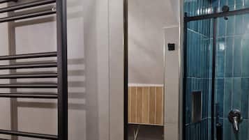 Une salle de bain avec un porte-serviettes noir, un lavabo blanc, un miroir et une douche aux carreaux bleus.