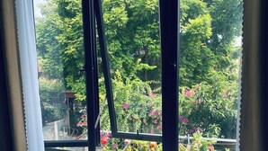A window with a view of a garden with various plants and flowers. - Tam Coc Phuong Nhi Homestay (Nam Hoa Lu)