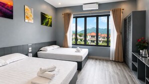 A hotel room with two beds, a large window with curtains, a view of buildings, and an air conditioning unit. - Tam Coc Phuong Nhi Homestay (Nam Hoa Lu)