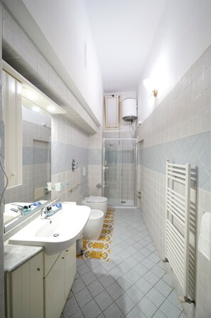 Ein Badezimmer mit zwei Waschbecken, einer Toilette, einer Dusche und einem Spiegel.