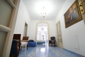 Un couloir avec un lit, une chaise et un lustre.