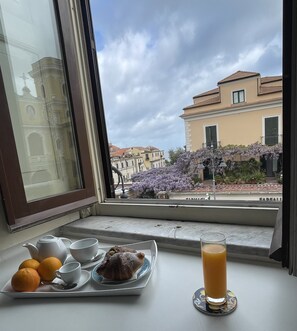 A breakfast tray with pastries, a glass of orange juice, and cups on a windowsill. - Ambasciata Sorrento Relais (Sorrento)