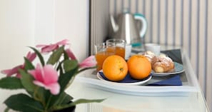 Un plateau de petit-déjeuner avec deux oranges, un croissant et un verre de jus d’orange, posé sur une table.