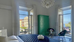 Een slaapkamer met een bed, een groene garderobe, een klein tafeltje met een vaas en een stoel.