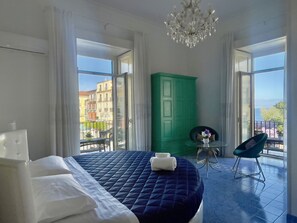 Ein Schlafzimmer mit einem Bett, einem grünen Kleiderschrank, einem kleinen Tisch mit einer Vase und einem Sessel.