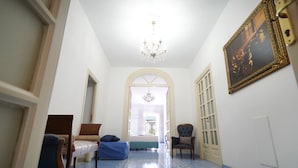 A hallway with a bed, a chair, and a chandelier. - Ambasciata Sorrento Relais (Sorrento)