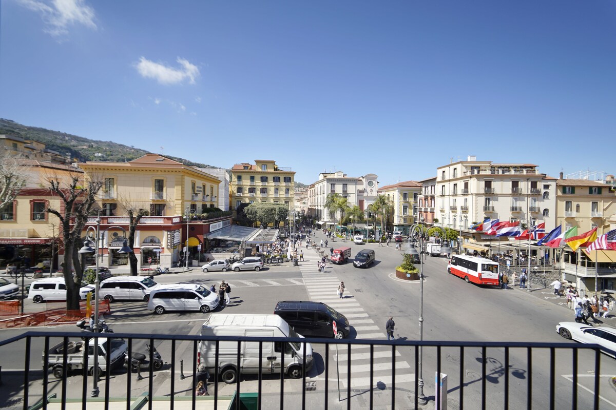 Eine belebte Stadtstraße mit Gebäuden, Fahrzeugen und Fußgängern.