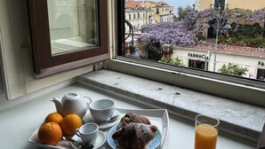 A breakfast tray with orange juice, a teapot, cups, and a pastry on a windowsill. - Ambasciata Sorrento Relais (Sorrento)
