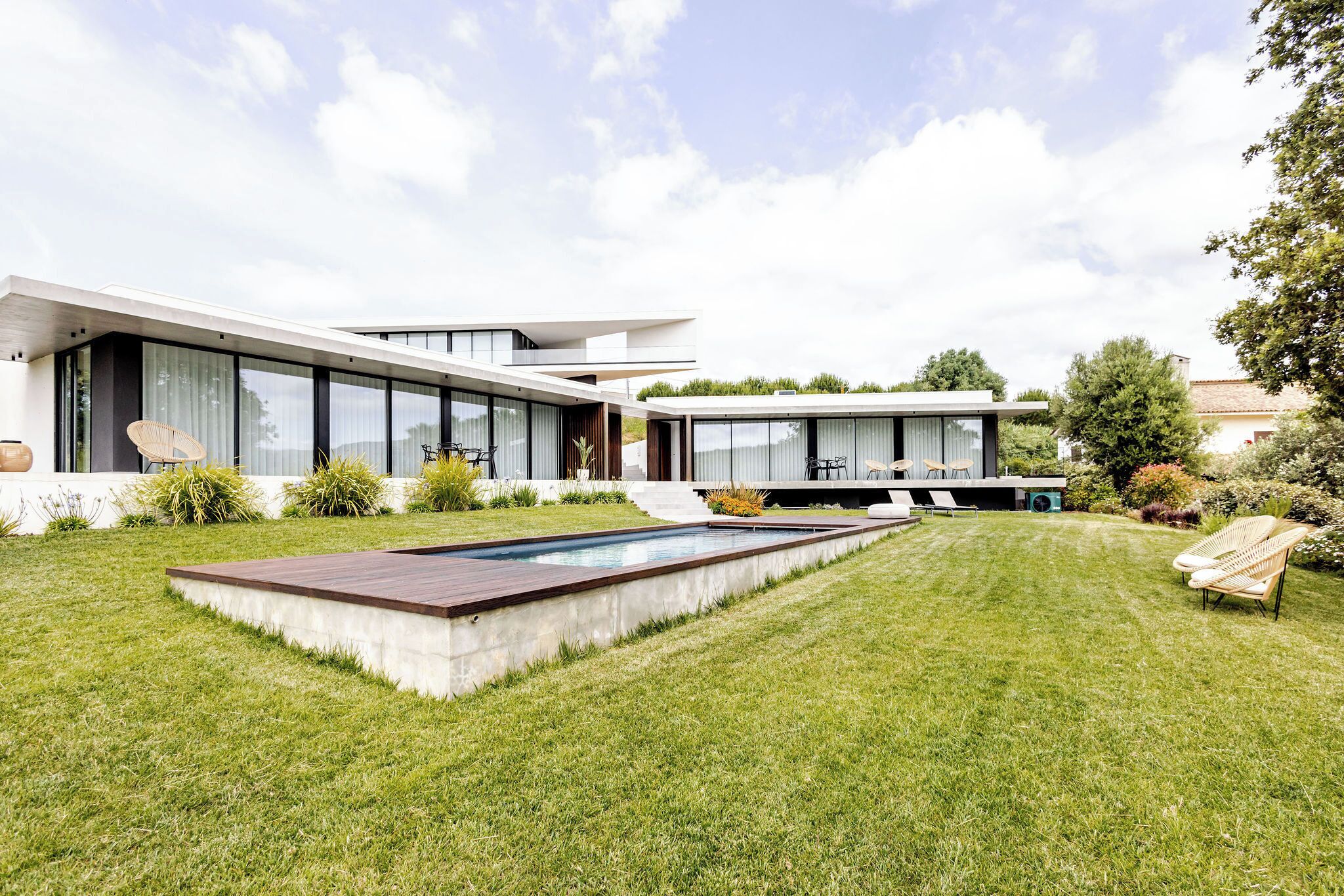 A modern house with a swimming pool, a well-maintained lawn, and outdoor furniture.